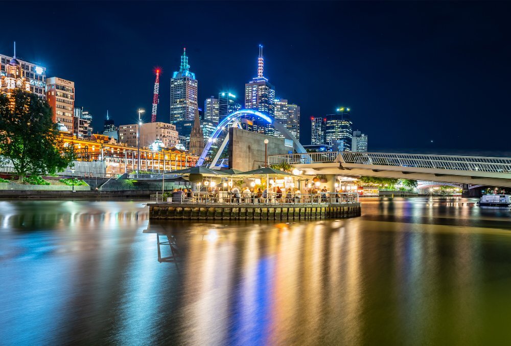 A floating bar on a river at night with the city skyline in the background