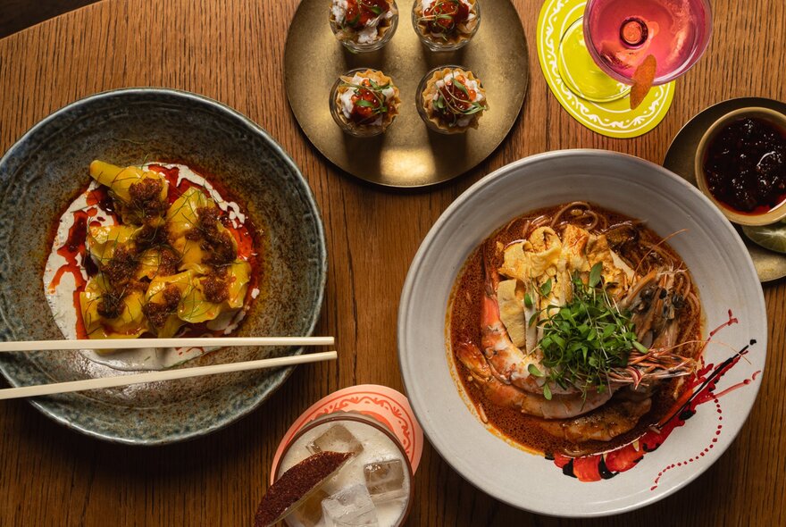 Looking down at dishes of Asian food with chopsticks and drinks.