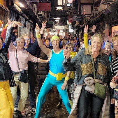 Group dancing in a Melbourne laneway, led by a man in a bright green and yellow shiny outfit.