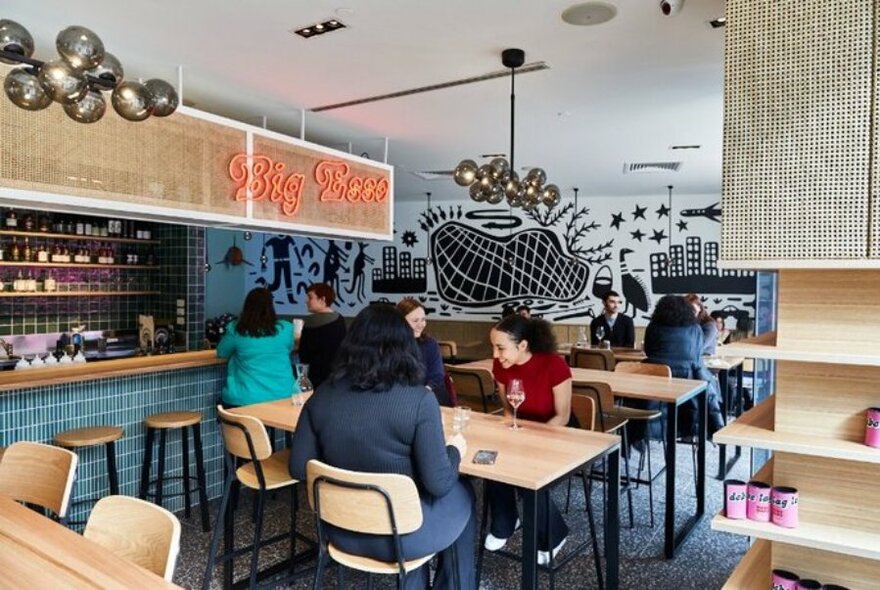 People sitting at tables within Big Esso restaurant in Fed Square. 