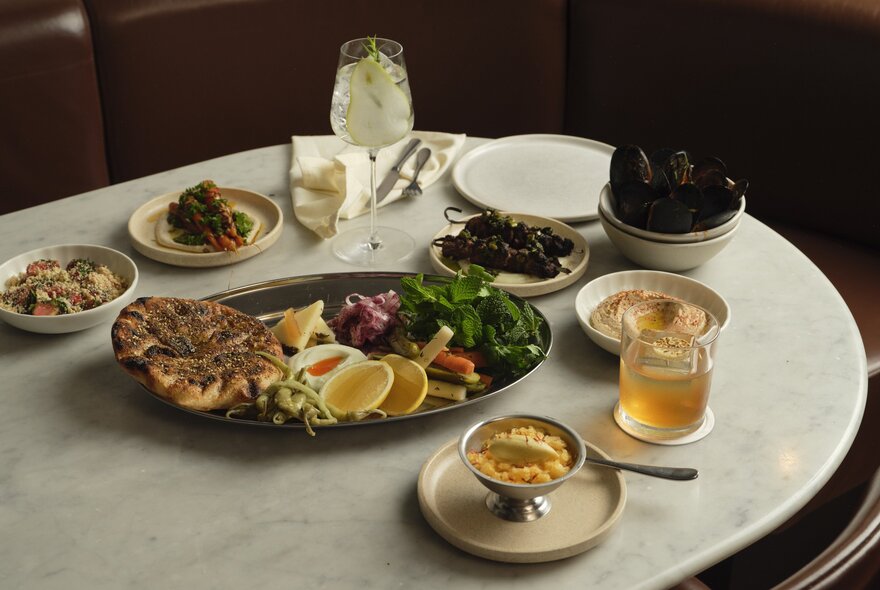 The mezze spread featuring wood-fired flatbread, fava bean hummus, and seasonal dishes on a white marble table at Nomad restaurant.