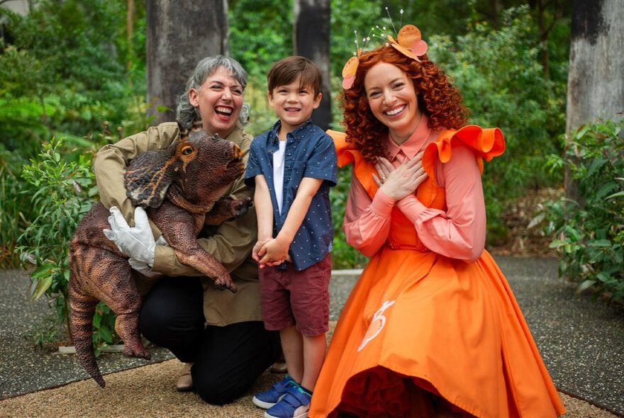 Children's performers in dress with an excited child in a garden setting.