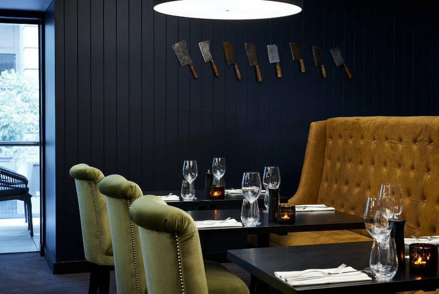 A restaurant dining room set for dinner with gold banquettes and chairs. 