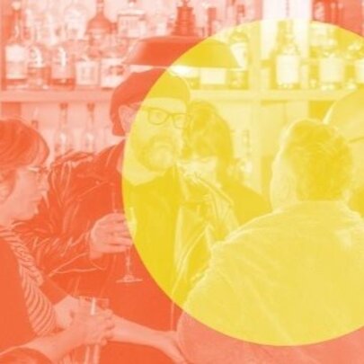 Social scene of four people gathered around a bar talking and interacting; there is large yellow circle superimposed over the orange coloured image.
