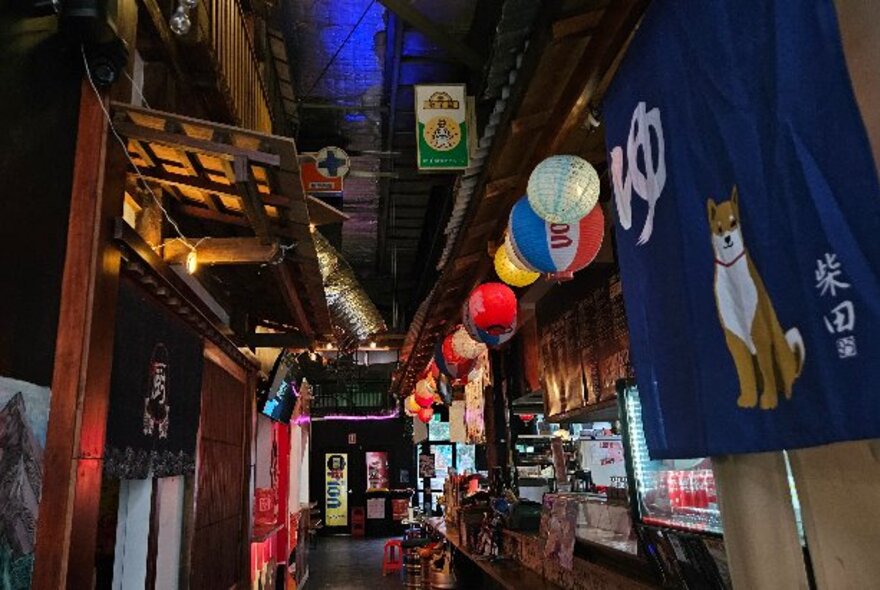 Outdoor market stalls with coloured hanging lanterns and small shopfronts