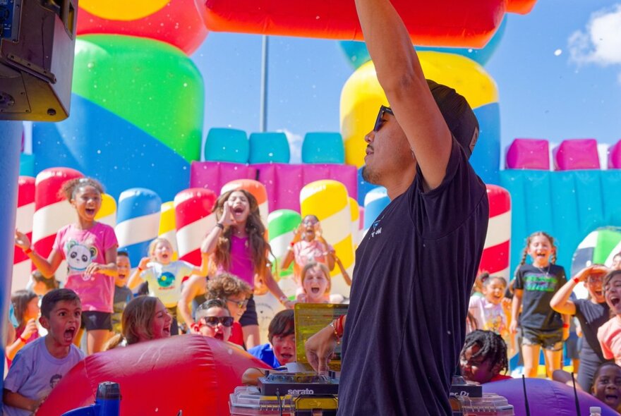 A DJ playing music to a group of excited young kids inside a giant inflatable.