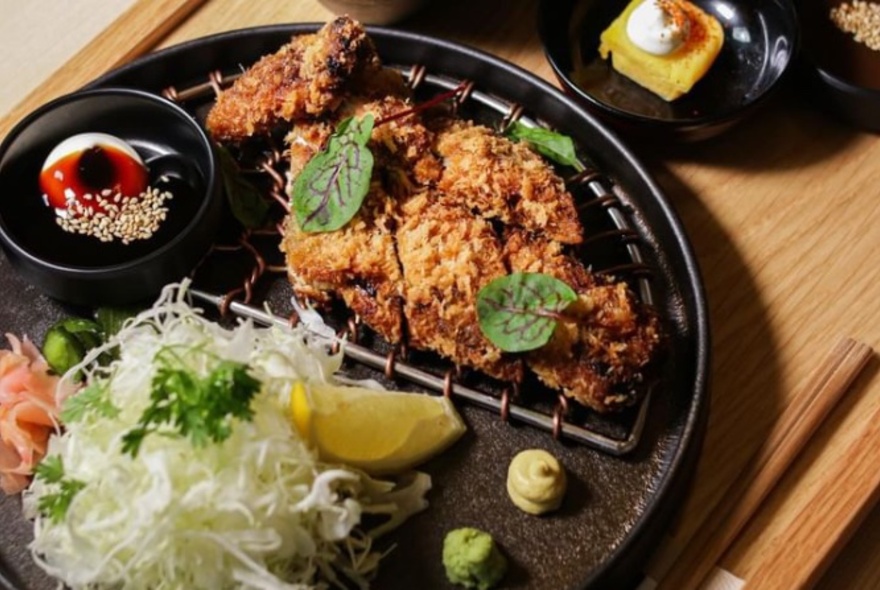 A plate with divide portions of katsudon and salad.