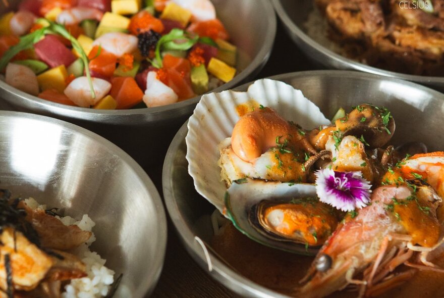 Stainless-steel bowls filled with salads and seafood.