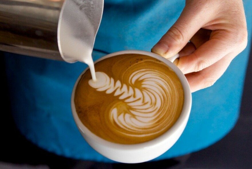 Frothed milk pored into a cup of coffee to create latte art.