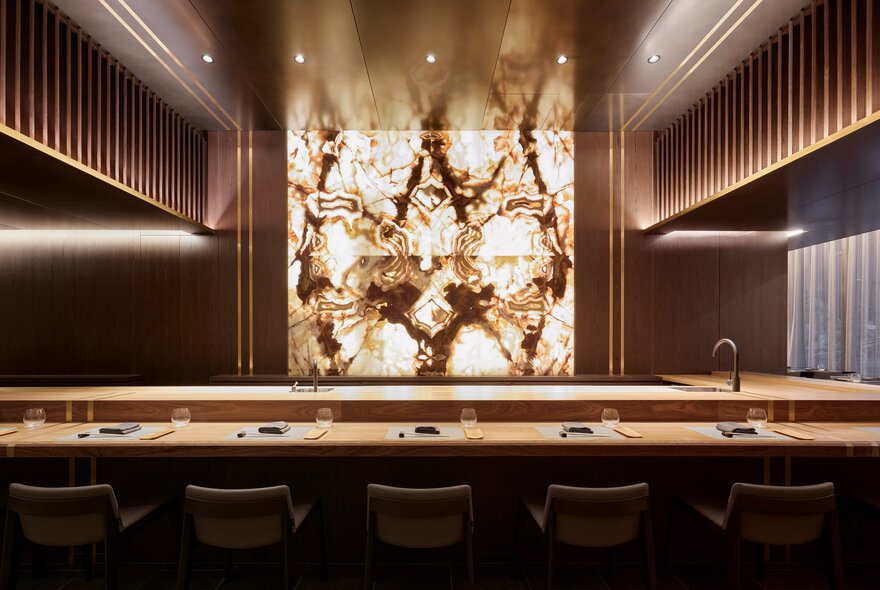 Backlit marble sushi bar in wood-decor spotlit restaurant.