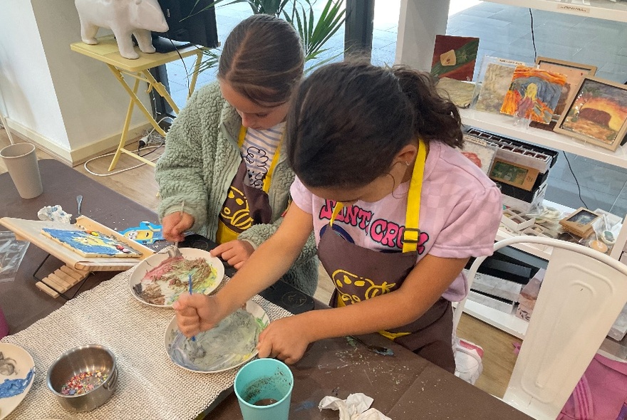 Two girls working hard on a painting project. 