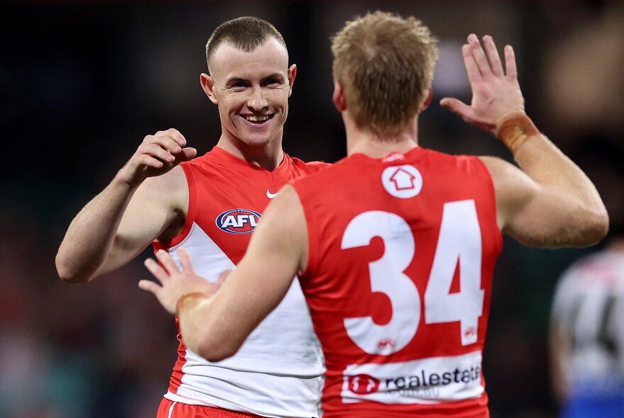 Sydney Swans AFL football players clapping hands during a match.
