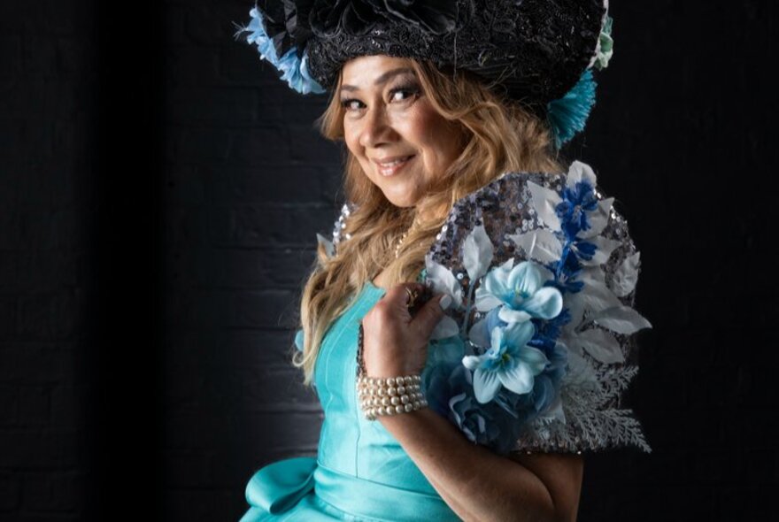 A Filipino Flores de Mayo pageant queen wearing an aqua blue silk dress with elaborate floral sleeves and a floral headdress. 