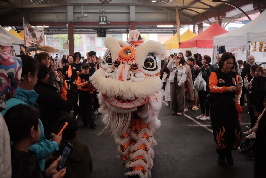 A traditional dragon dance with onlookers in a public outdoor space.