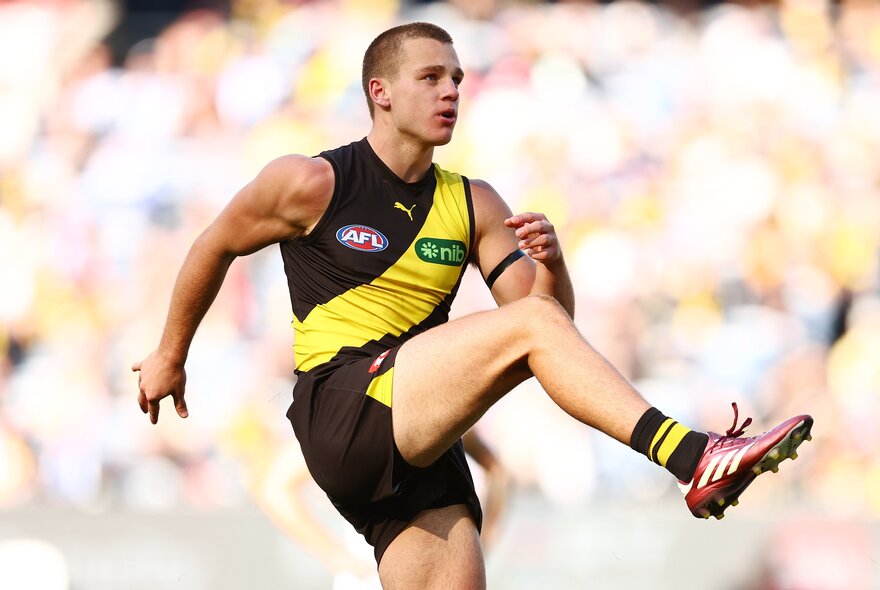 Richmond AFL football player kicking a ball during a match.