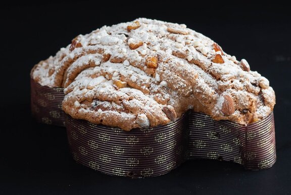 A colomba pasquale Easter cake with an airy golden-brown crumb, whole almonds and a dusting of icing sugar.