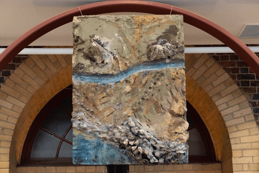 Panel artwork made from oyster shells, hung from an arch over an arched lintel.