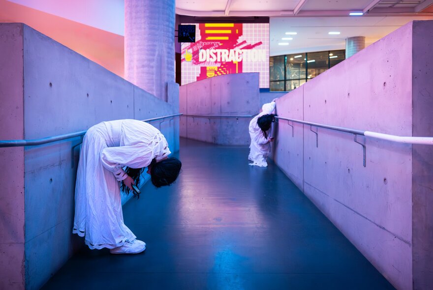 Performers in white in a concrete gallery space.