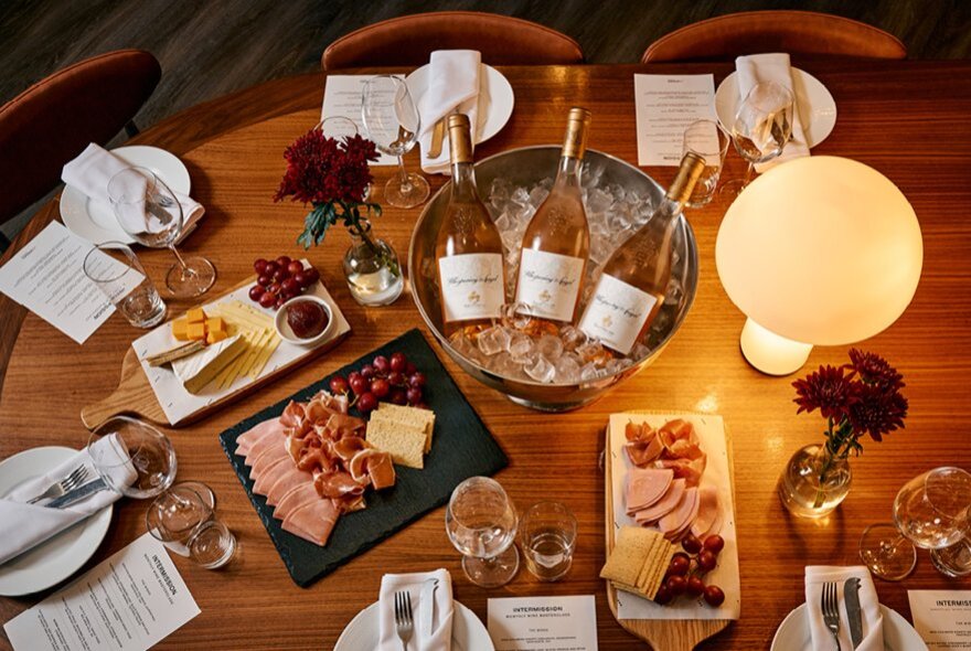 A table set for six, with a charcuterie board, cheese platters and wine on ice.
