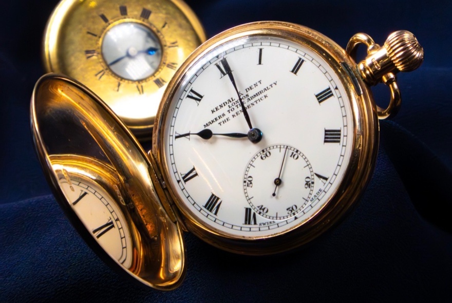 A gold pocket watch with a mirrored surface on the inner lid.