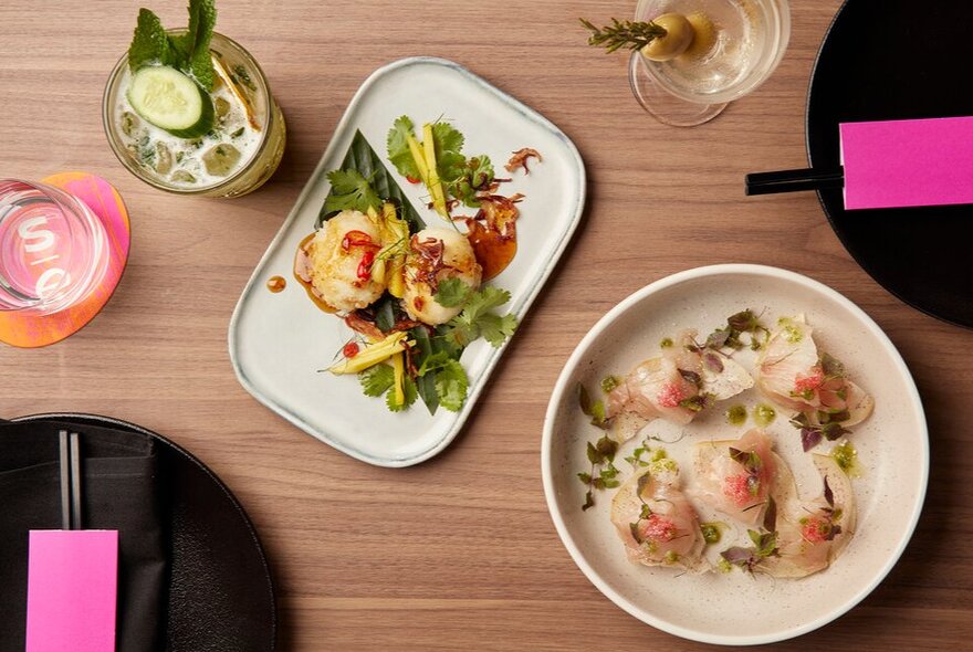 A range of Asian dishes on a table with chopsticks and drinks.