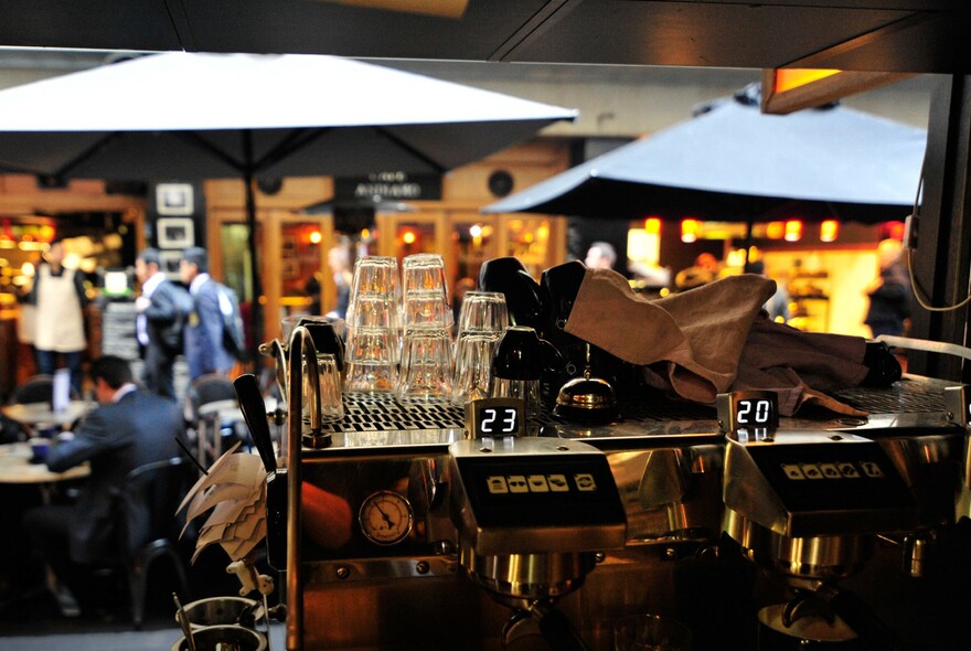 View looking out of the cafe into Degraves Street, showing the coffee machine and people seated under umbrellas outside.