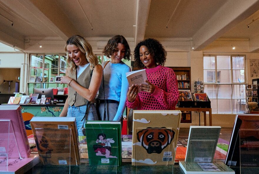 Three people looking at books in a display of books in an elegant bookstore.