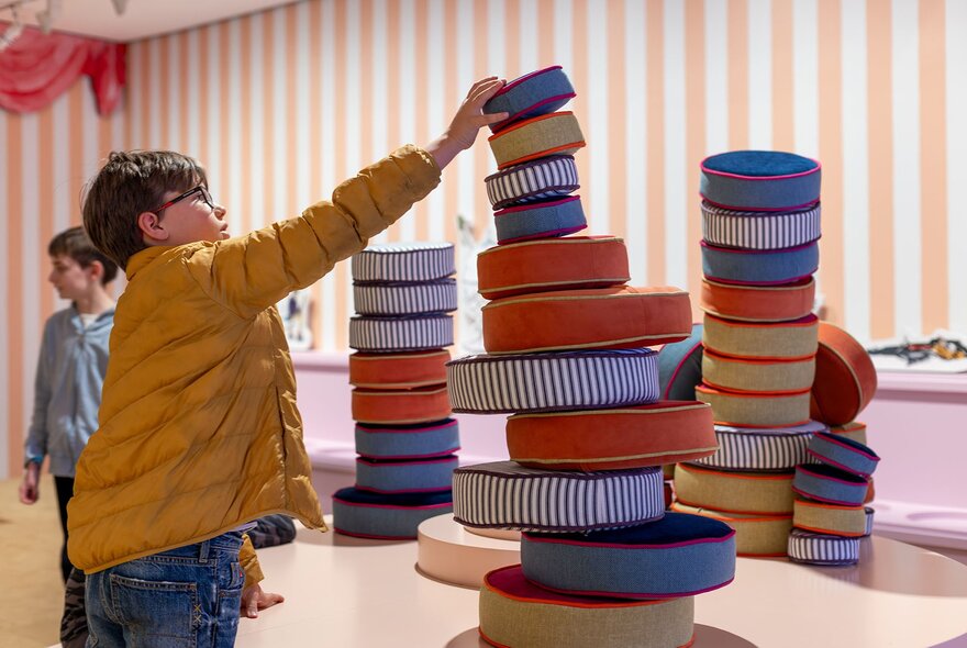 A child stacking colourful cushions.