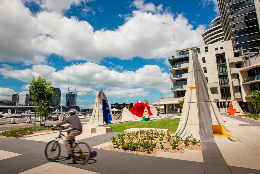 Cyclist passing a sculpture park on NewQuay Promenade.