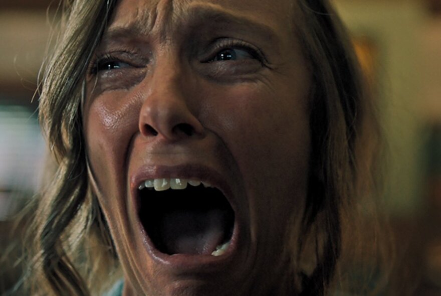 A woman screaming in anguish with her mouth open. 