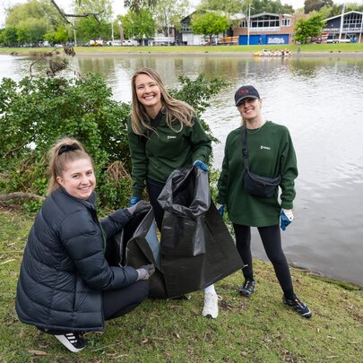 People with garbage bags collecting rubbish on the banks of the Yarra.