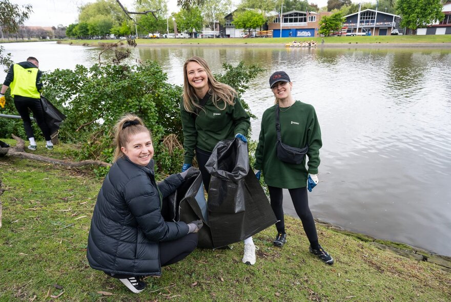 People with garbage bags collecting rubbish on the banks of the Yarra.