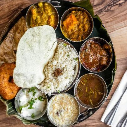 Thali Indian multicourse dish with rice, bread and raita, with cutlery.