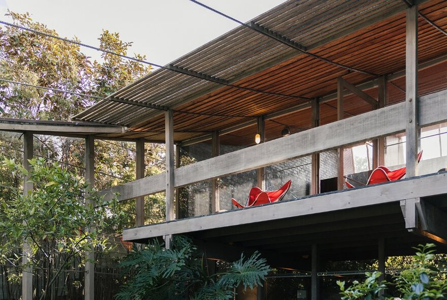 The exterior of a home with a wooden balcony and foliage. 