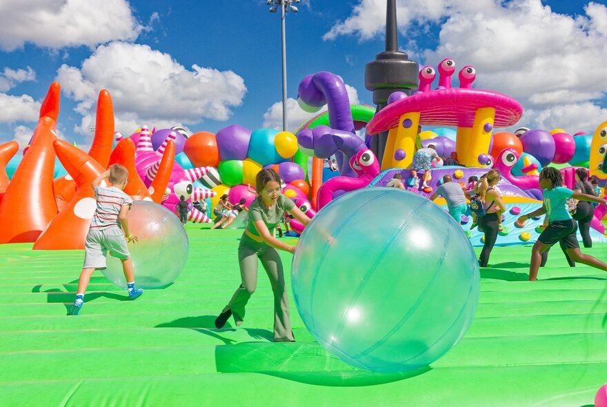 Kids jumping and bouncing on a giant inflatable and rolling large balls.