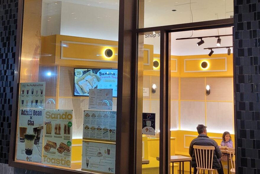 A Hong Kong-style cafe with yellow interiors, seen from outside the shop.