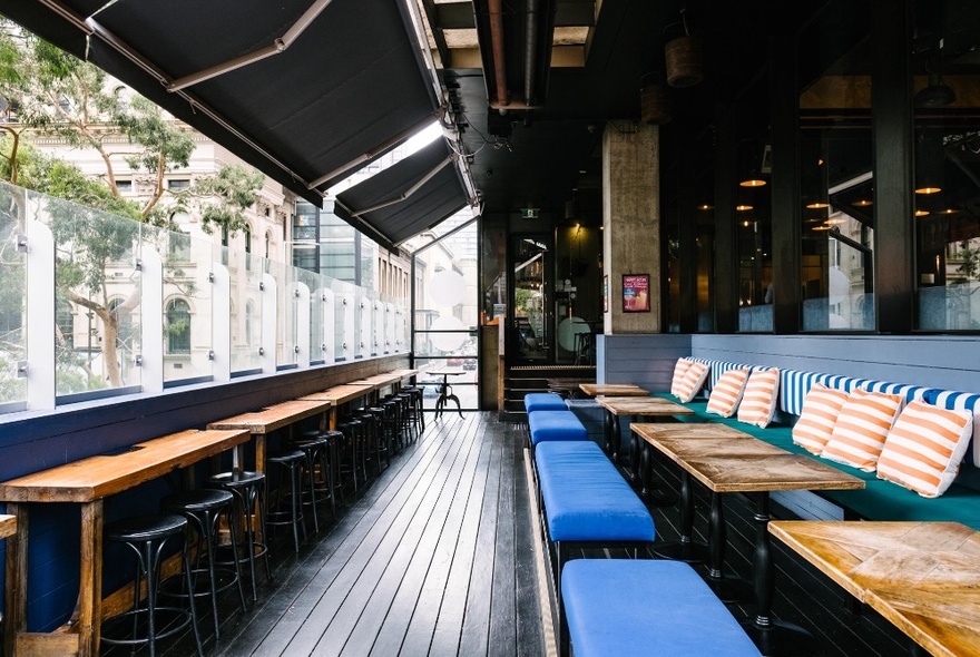 The wraparound outdoor balcony of Father's Office, with bench seating along the walls and high tables and stools on the opposte side.
