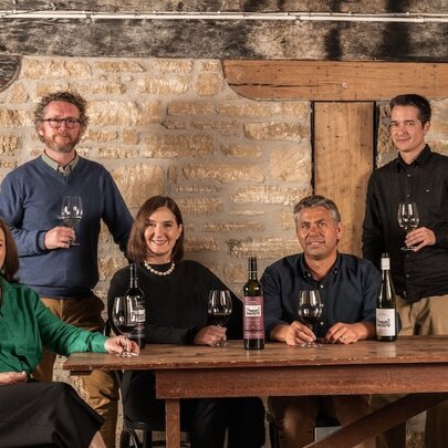 A group of winemakers and staff seated around a table, with bottles and glasses of wine, in a stone room at Wynns Coonawarra Estate. 
