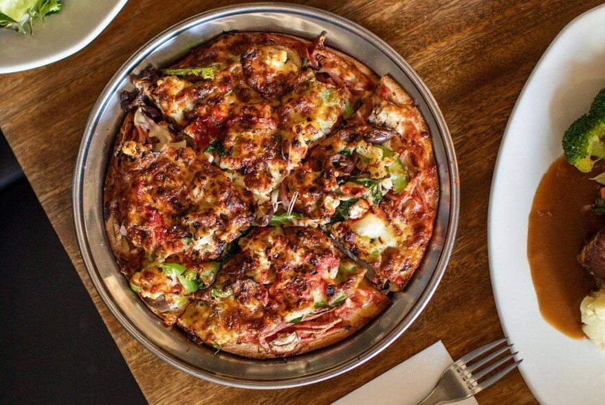 Meat pizza on a metal tray.