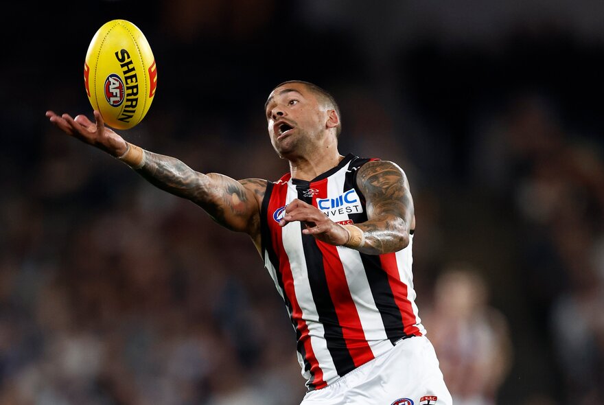 A St Kilda AFL player with outstretched arms and hands about to mark the footy.
