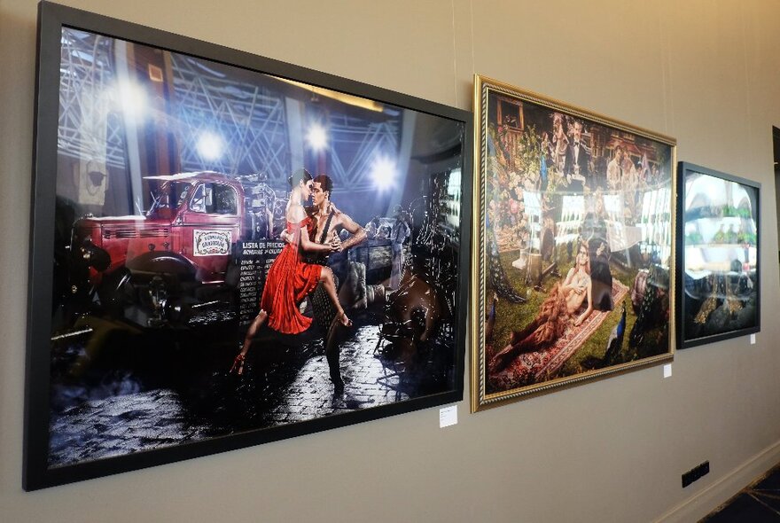 A white wall in a room lined with large scale framed photographic works.