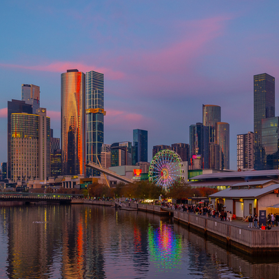 Pink sunset clouds over the city skyline and a Ferris wheel.