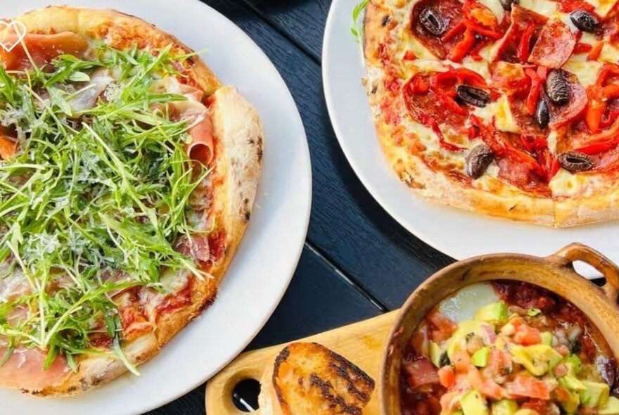 Two traditional wood-fired Italian pizzas and a bowl of soup.