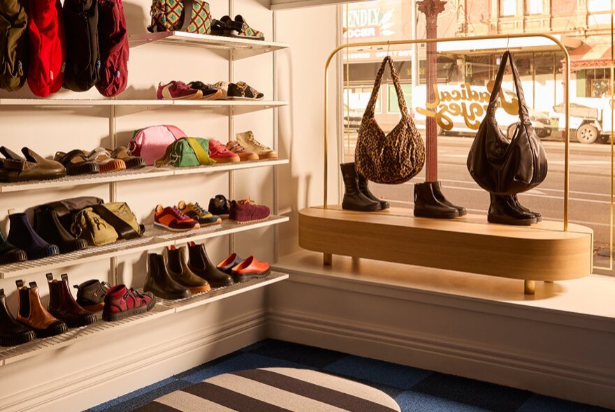 Shop window with shelves of shoes and hanging handbags.