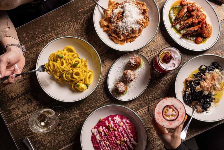 Top down view of a plates of food, arranged on a wooden table in a restaurant. 