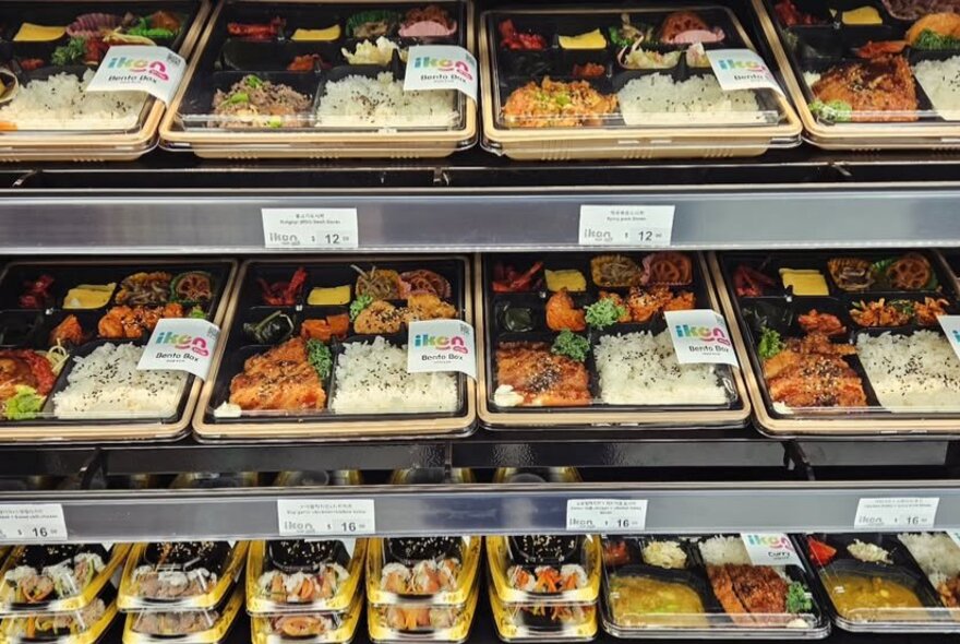 Storage shelves of takeaway Korean mea;s and sushi.