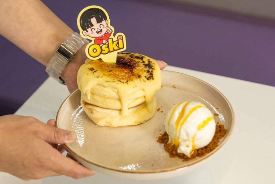 A plate of Japanese soufflés with ice cream and a business tag showing a cute cartoon. 