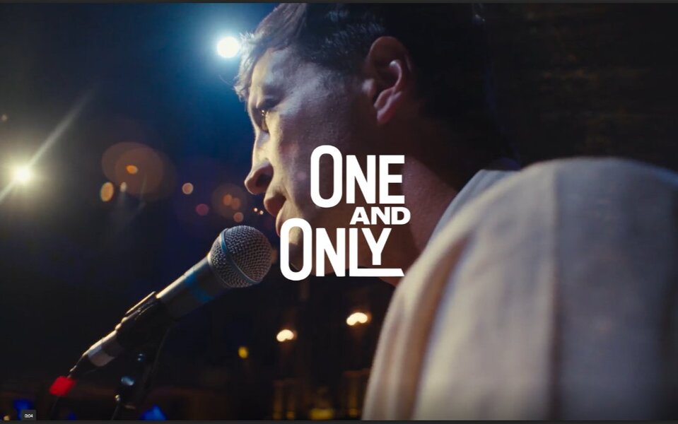 A man speaking into a microphone with the text 'One and Only' overlaying the image.