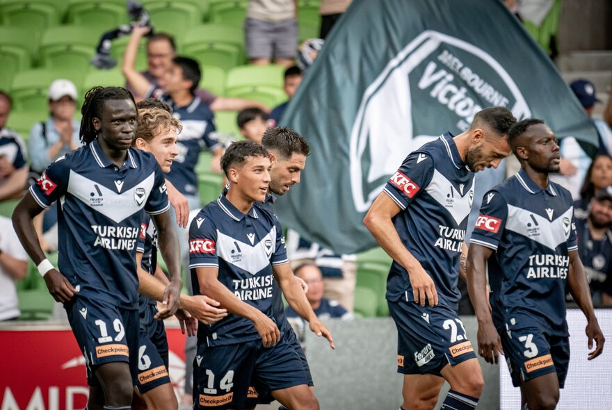 Members of Melbourne Victory walking on the field at a match. 