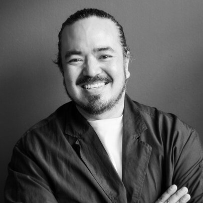 Adam Liaw, smiling with his arms folded.
